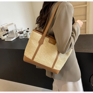 Straw tote bag detail with brown leather trim and fashion label on a cafe background
