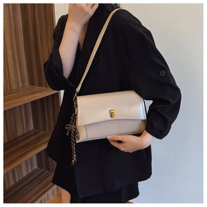 Détail du sac bandoulière en cuir ciré avec fermoir doré et pendentif tressé élégant