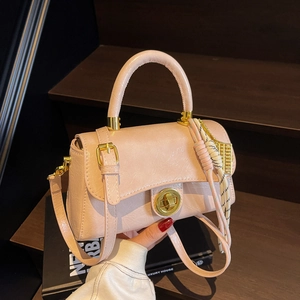 Sac bandoulière rose élégant avec fermoir doré et poignée tressée sur livres de luxe