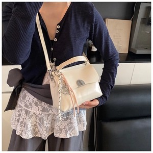 Close-up of cream soft leather tote bag with silver buckle and decorative pendant