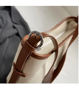 Detail of cream pebbled leather tote with caramel trim and adjustable shoulder strap