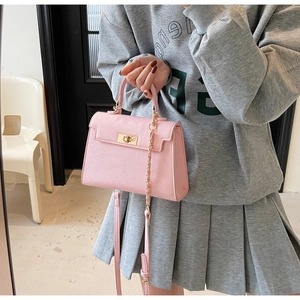 Detailed view of pink trapezoid handbag with gold metal twist lock and cross grain leather