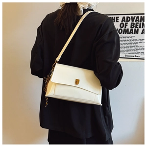 Détail d'un sac porté épaule en cuir blanc avec un fermoir tournant rectangulaire doré