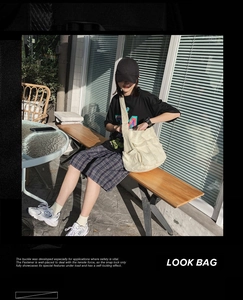 Detail of beige canvas crossbody bag featuring multi-pocket utility design and wide strap