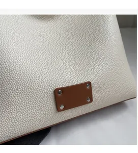 Detail of white lychee grain leather handbag with brown patch and silver rivet accents