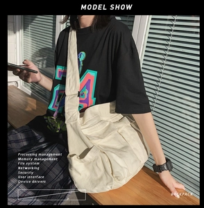 Detail of a large off-white canvas messenger bag with wide strap and multi-pocket design
