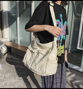 Detail of off-white canvas messenger bag with double front flap pockets and wide strap
