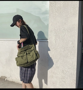 Close-up of olive green canvas messenger bag featuring vintage flap pockets and texture