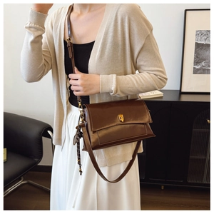 Détail d'un sac à bandoulière vintage marron foncé avec boucle dorée dans un intérieur