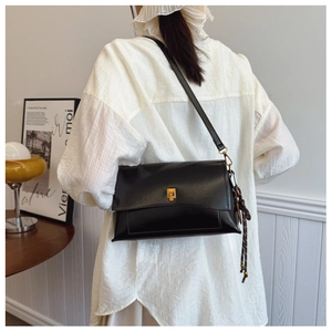Détail du sac bandoulière en cuir ciré noir avec élégant fermoir rotatif doré