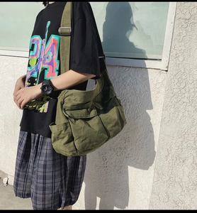 Detail of army green canvas crossbody bag with double flap pockets and wide strap