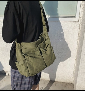 Detail of army green canvas crossbody bag featuring multi-pocket utility design
