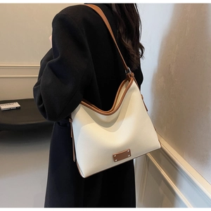 Side view of cream pebble leather hobo bag with brown trim worn by a model