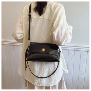 Vue arrière du mannequin portant un sac bandoulière en cuir ciré noir avec boucle dorée