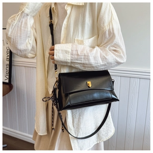 Détail d'un sac à bandoulière en cuir ciré noir vintage avec boucle dorée sur un mannequin