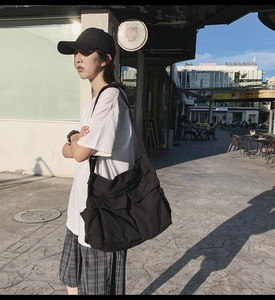 Street style shot of a black multi-pocket canvas crossbody bag with wide straps