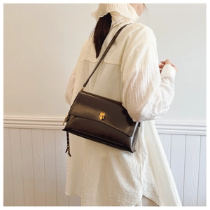 Détail du sac bandoulière vintage en cuir marron foncé avec fermoir doré et pendentif tressé