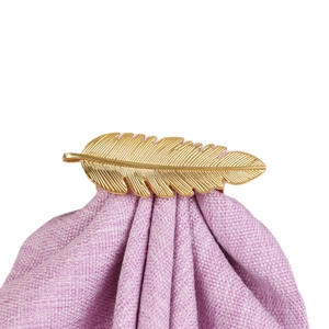 Rond de serviette plume dorée en alliage sur une serviette en lin violet élégante