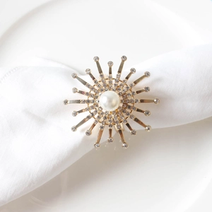 Close-up of golden starburst napkin ring with pearl and crystal rhinestones on a white cloth