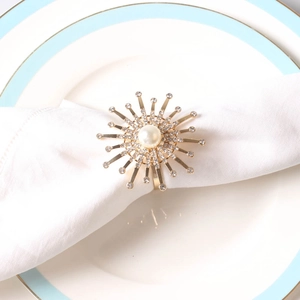 Detail of a golden sunflower napkin ring with pearls and rhinestones on a white napkin