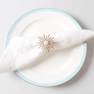 Macro view of golden sunflower napkin ring with pearl and crystals on white cloth