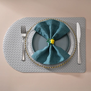 Primer plano de servilletero de limón amarillo sobre tela azul y plato con cuentas doradas