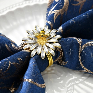 Rond de serviette marguerite dorée avec petite abeille sur une serviette bleu marine