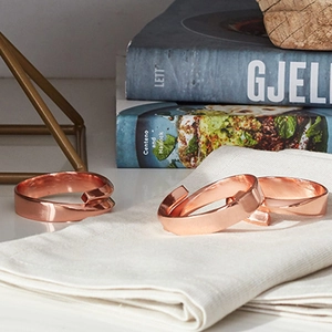 Set of three rose gold polished metal napkin rings with a spiral open design for decor