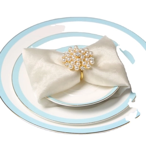 Elegant gold napkin ring featuring white pearls and rhinestones on a ceramic dinner plate