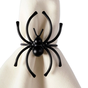 Detail of a matte black spider napkin ring on a cream fabric cloth for Halloween decor