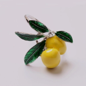 Detalle de servilletero de limón con frutas amarillas y hojas de esmalte verde sobre metal