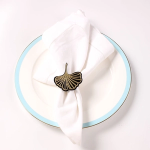 Detailed view of a gold ginkgo leaf napkin ring set on a white ceramic dinner plate