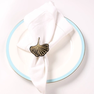 Close-up of golden ginkgo leaf napkin ring on white napkin for elegant table decor