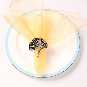 Detailed view of a black ginkgo leaf napkin ring with gold edges on a ceramic plate