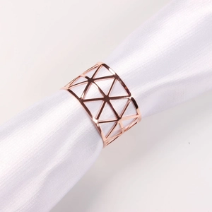 Detail of rose gold hollow triangular napkin ring on a white fabric holder roll