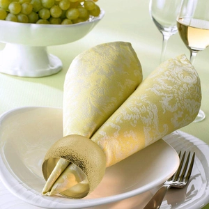 Gros plan d'un rond de serviette martelé doré sur assiette blanche avec décor élégant