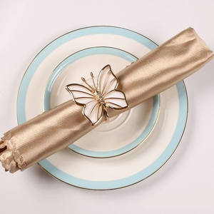 Golden butterfly napkin ring with white enamel and rhinestones on a white ceramic plate