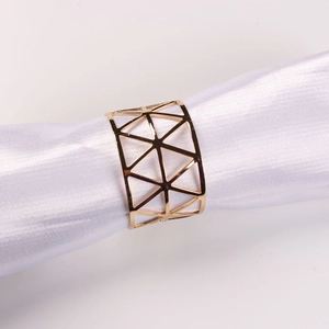 Golden geometric hollow X-shaped metal napkin ring displayed on white satin cloth