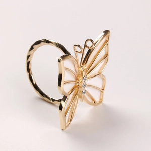 Detailed side view of golden butterfly napkin ring with white shells and diamond accents