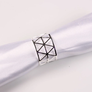 Close-up of silver metal napkin ring with geometric triangle hollow design on satin