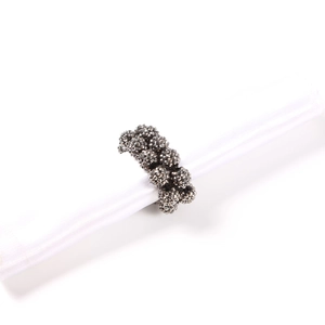 Macro shot of dark grey beaded napkin ring with faceted crystal cluster on white cloth