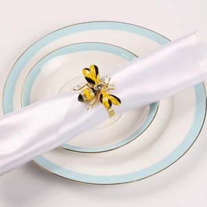 Golden bee napkin ring with yellow enamel and crystal on a white fabric napkin
