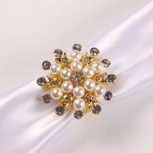 Detailaufnahme des goldenen Perlen-Serviettenrings in Blumenform mit Strasssteinen