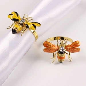 Detailed macro view of bee-shaped napkin rings with crystal inlay and gold-plated finish