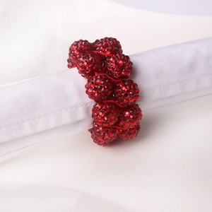 Close-up of red beaded napkin ring with sparkling rhinestones on a white linen napkin