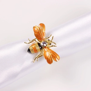 Exquisite gold bee napkin ring with orange enamel and crystal on white satin fabric