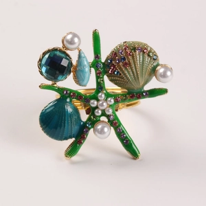 Détail d'un rond de serviette étoile de mer et coquillage avec strass et base dorée