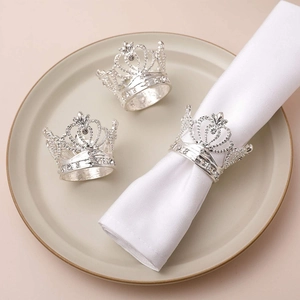 Detailed view of silver crown napkin rings with crystals on a white fabric napkin