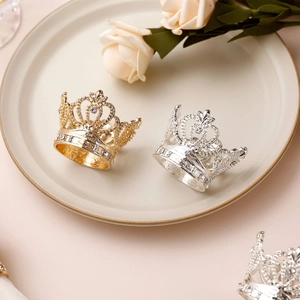 Detailed view of gold and silver crown napkin rings with rhinestones on a plate