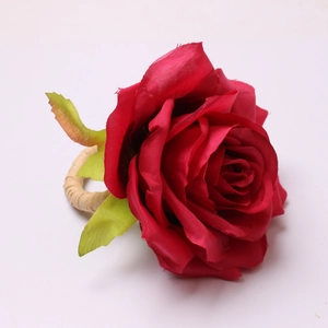 Detail of handmade red fabric rose napkin ring with woven texture and green leaves